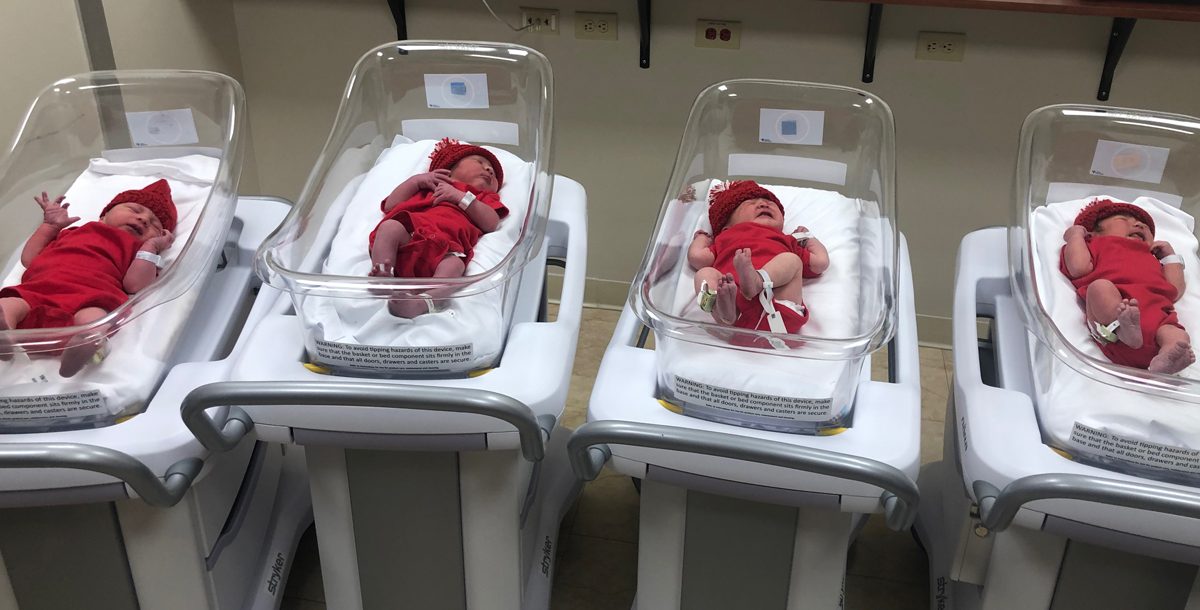 Newborn babies in hospital wear red onesies and hats for american heart month