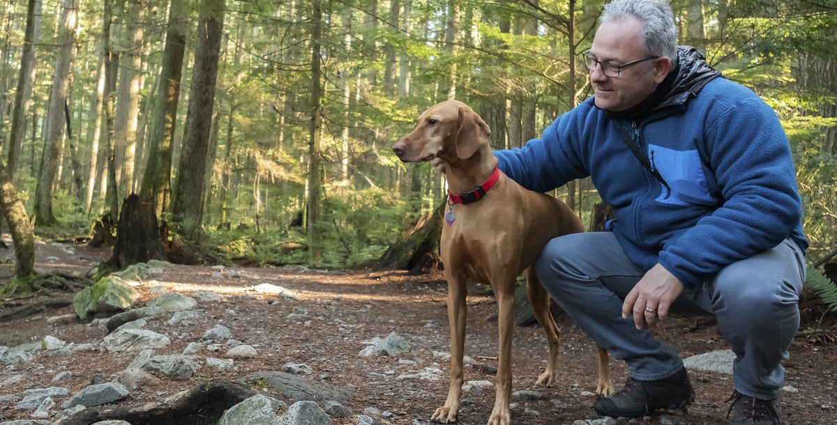 Man practicing social distancing with his dog in the woods
