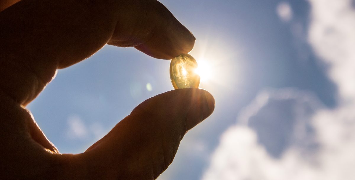 Vitamin D pill with the sunlight in the background.
