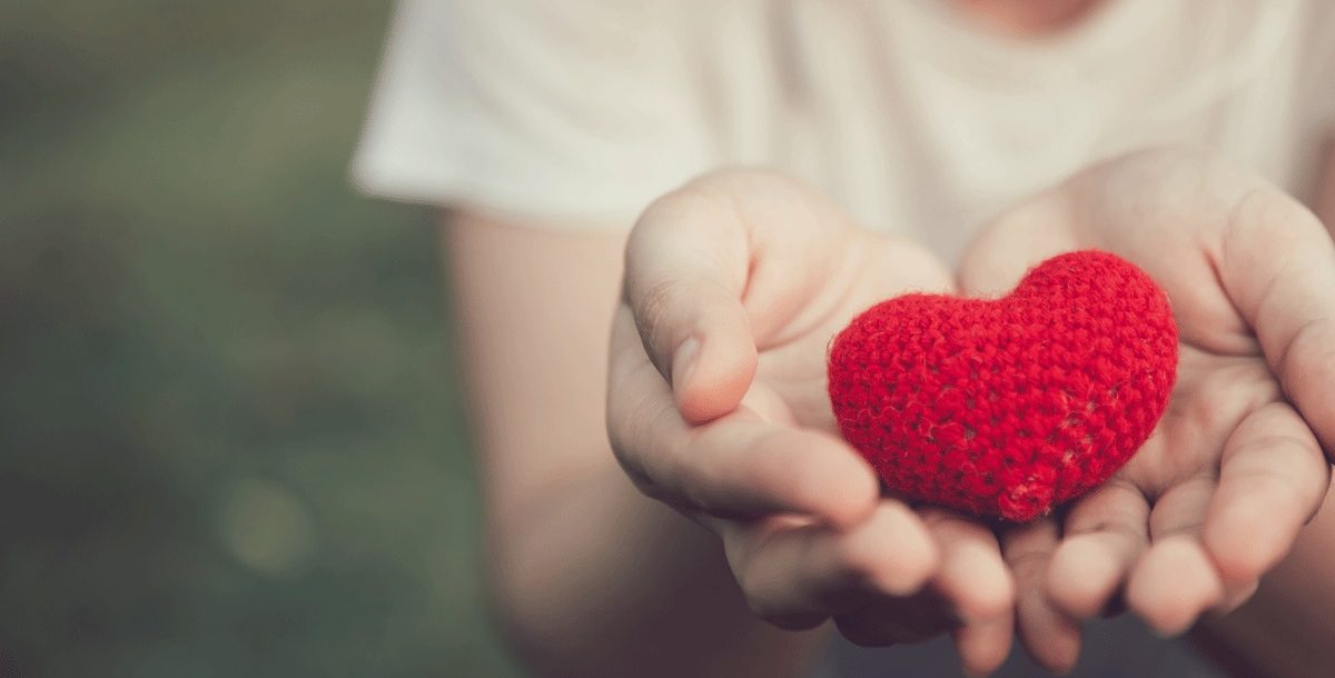 An individual holding a toy heart in their hands during a reflection.