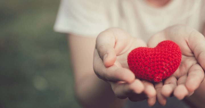 An individual holding a toy heart in their hands during a reflection.