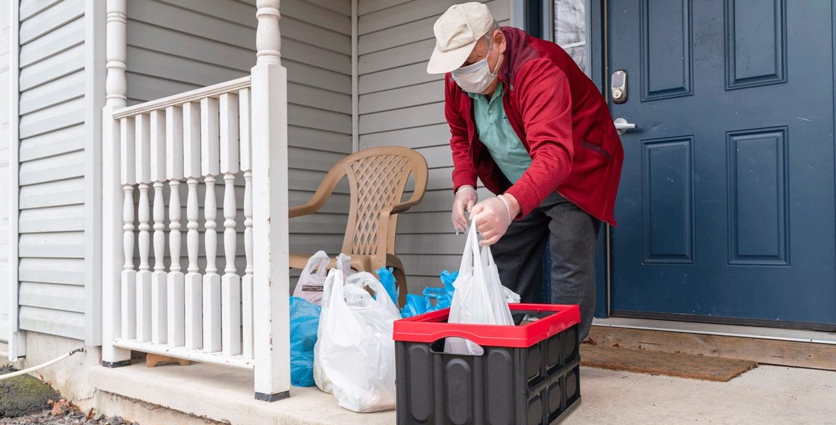 Older individuals taking grocery delivery into the house during COVID-19.