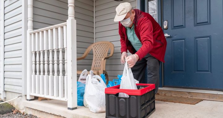 Older individuals taking grocery delivery into the house during COVID-19.