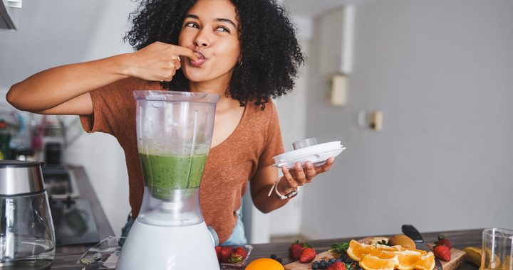 A woman making a healthy smoothie in her kitchen.