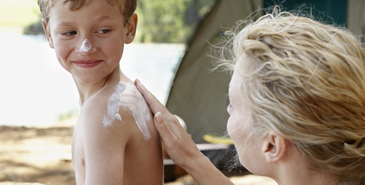 A mother applying sunscreen to her son's back.