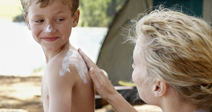 A mother applying sunscreen to her son's back.