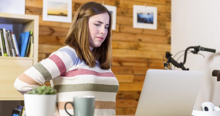 A women experiencing back pain while working remotely during COVID-19.