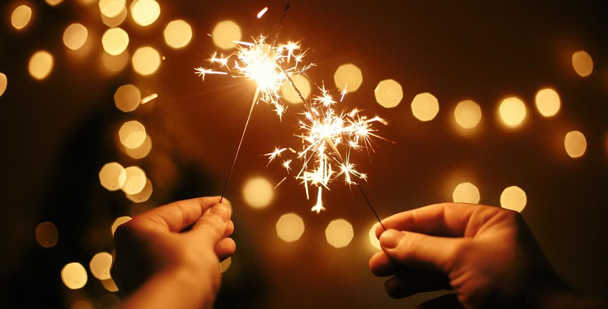 Two people holding sparkler fireworks.