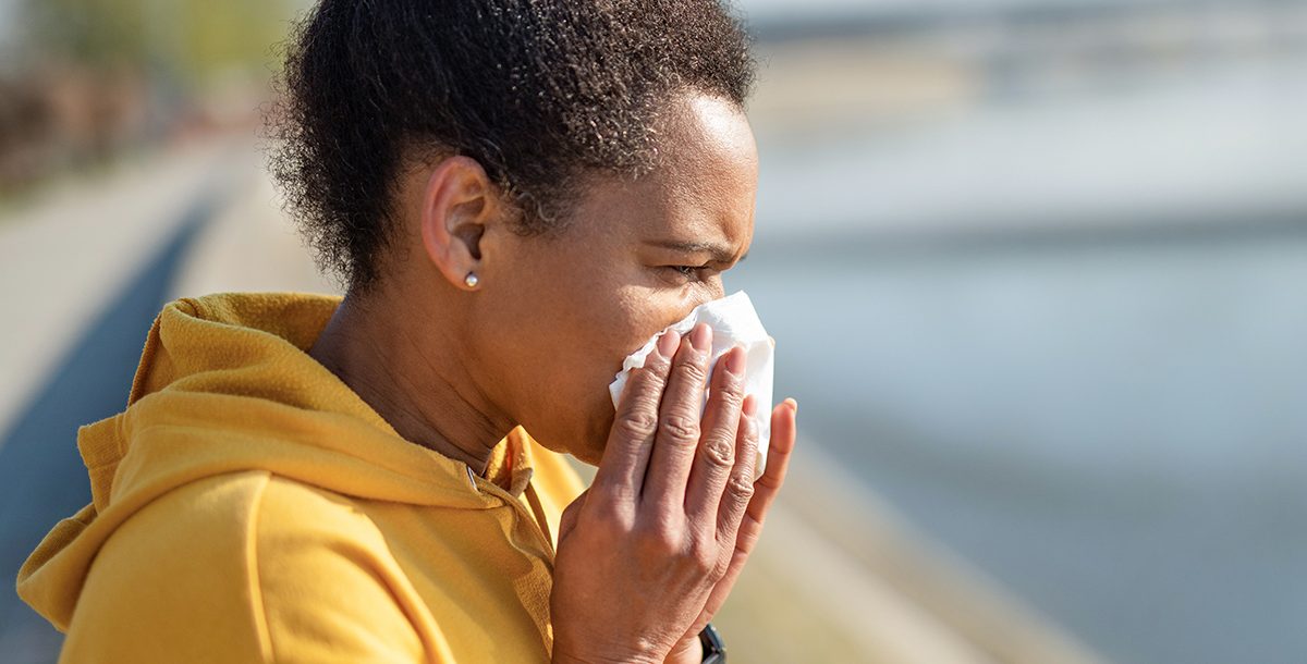 A woman sneezing into a tissue during COVID-19