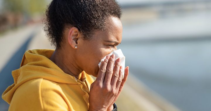 A woman sneezing into a tissue during COVID-19