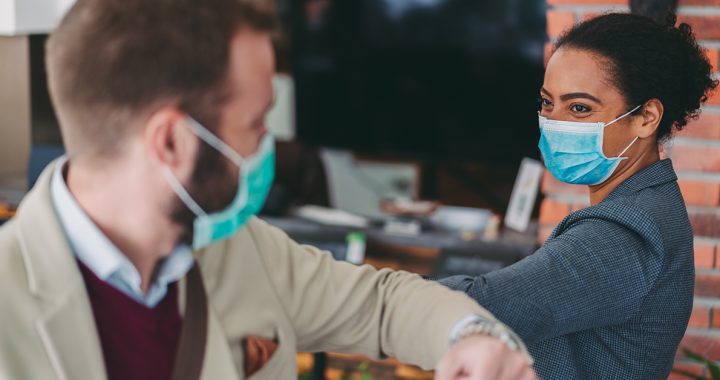 Two people wearing their face masks in public.