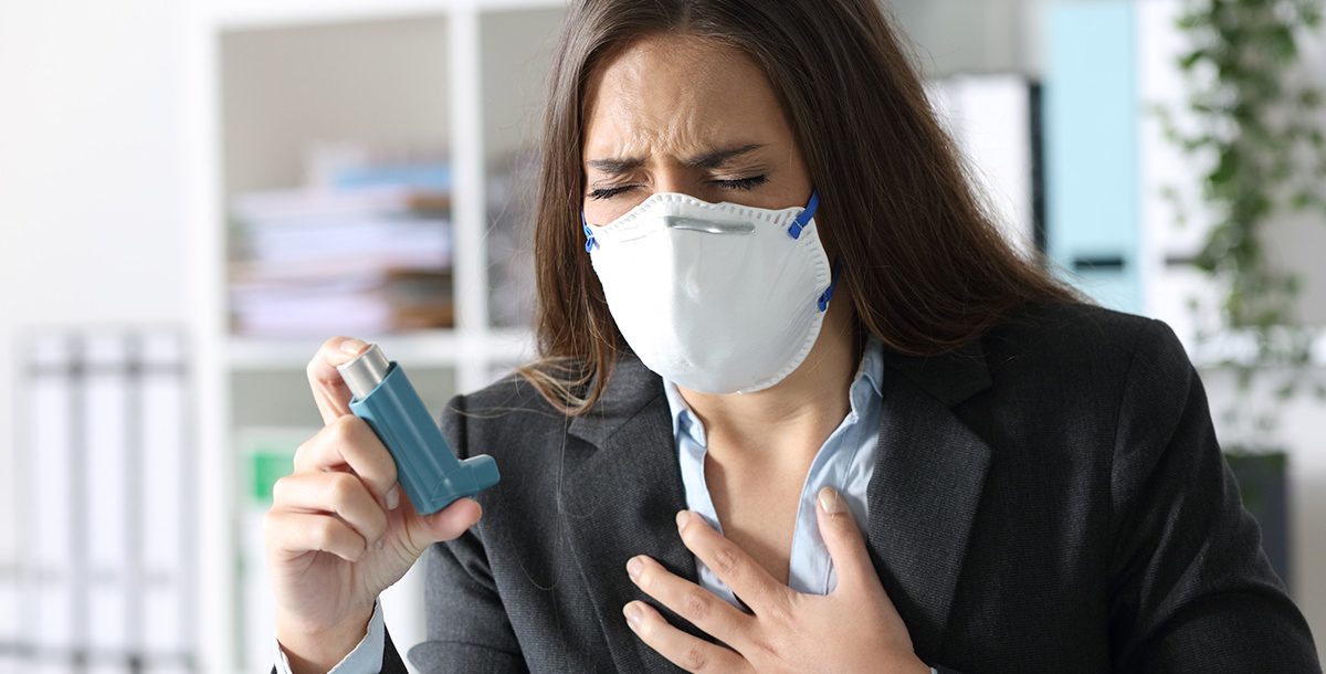 A woman suffering from asthma and using an inhaler.
