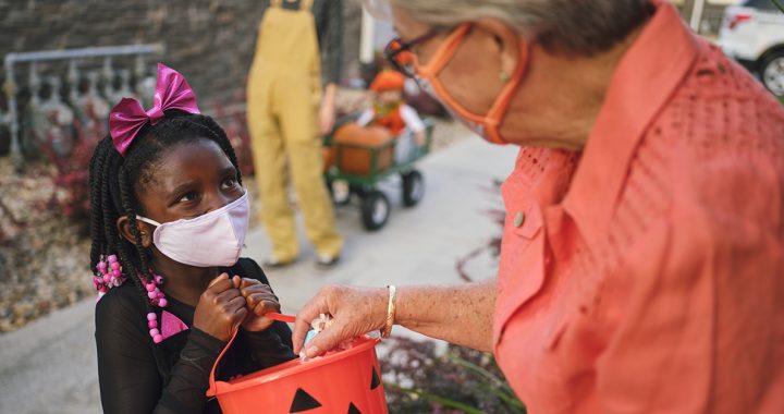 A child trick or treating with a face mask on during Halloween.