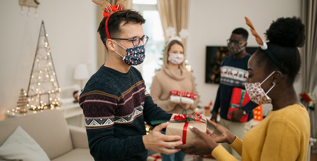 Friends hosting a holiday party with safety precautions.