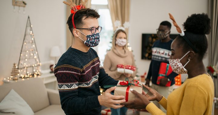 Friends hosting a holiday party with safety precautions.