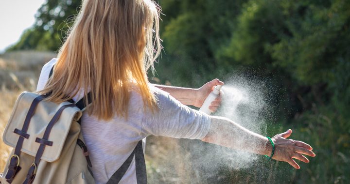 A woman putting on bug spray.